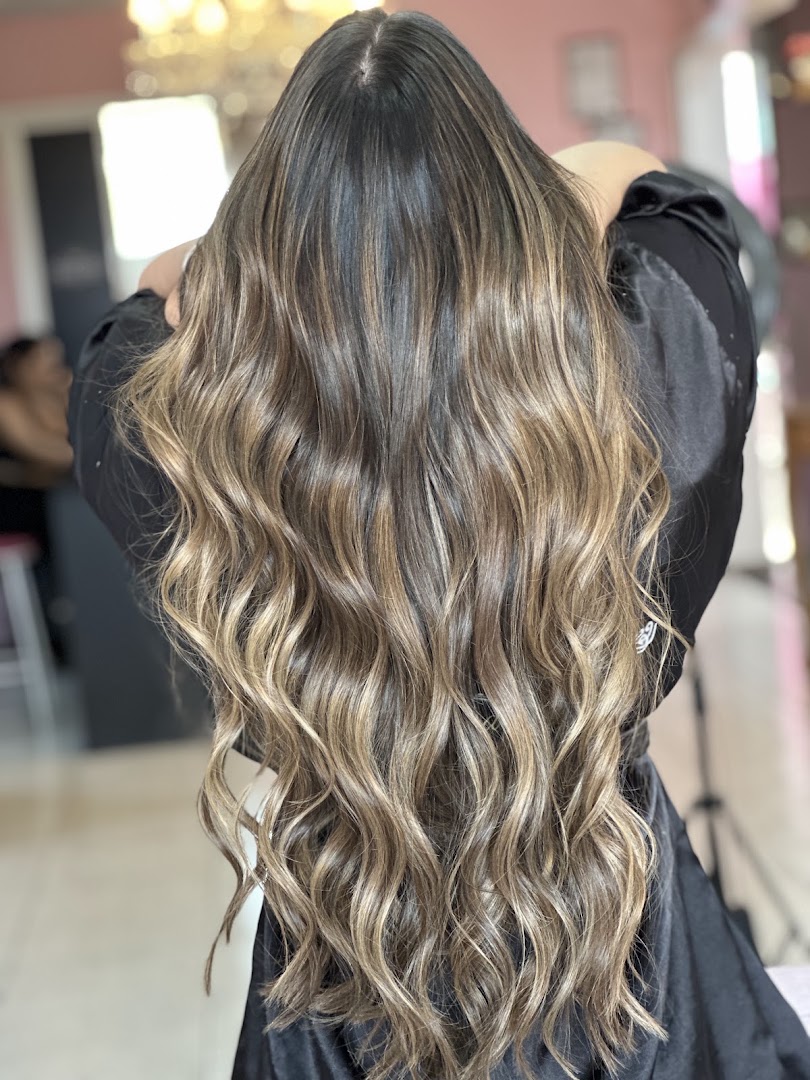 Cabelo com mechas loiras em ondas, cliente no salão com lustre dourado ao fundo